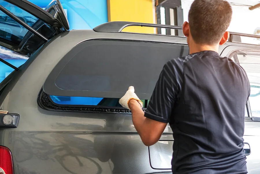 A technician wearing gloves replacing a vehicle's side window